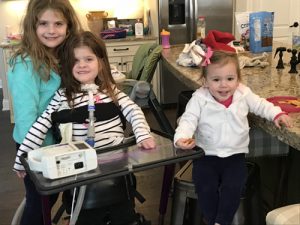 The Sims sisters: Catherine, a SMARD survivor, with older sister Molly and younger sister Caroline. Catherine is standing with the aid of a device.