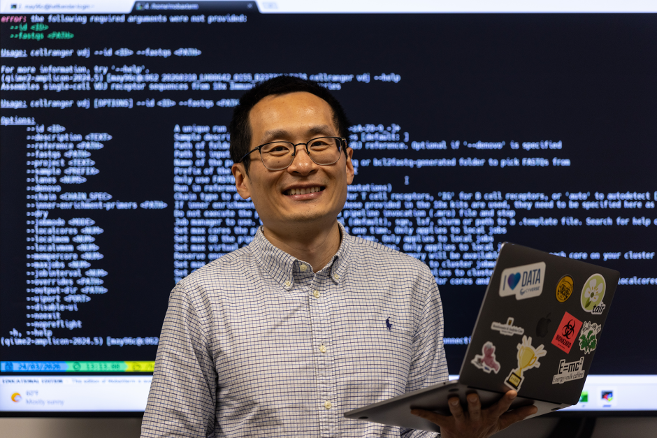 Hong An posing in front of computer code in his lab.